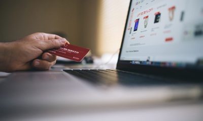 Mano de una persona disponiendose hacer una compra desde un computador con Tarjeta de crédito